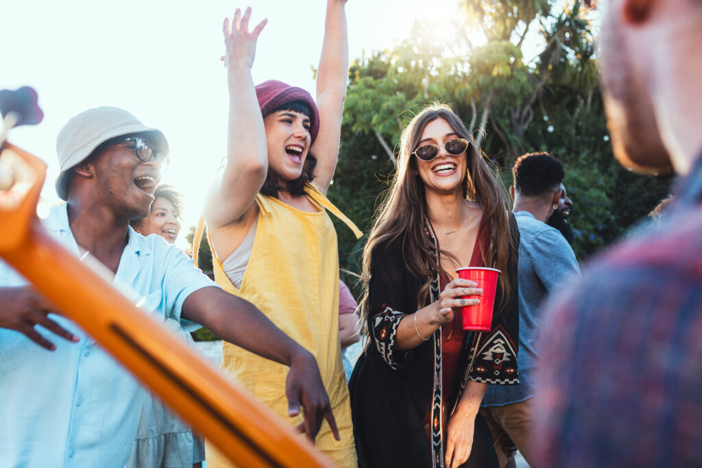 Music, drinks and friends dancing outdoor to celebrate at festival, concert or summer social event